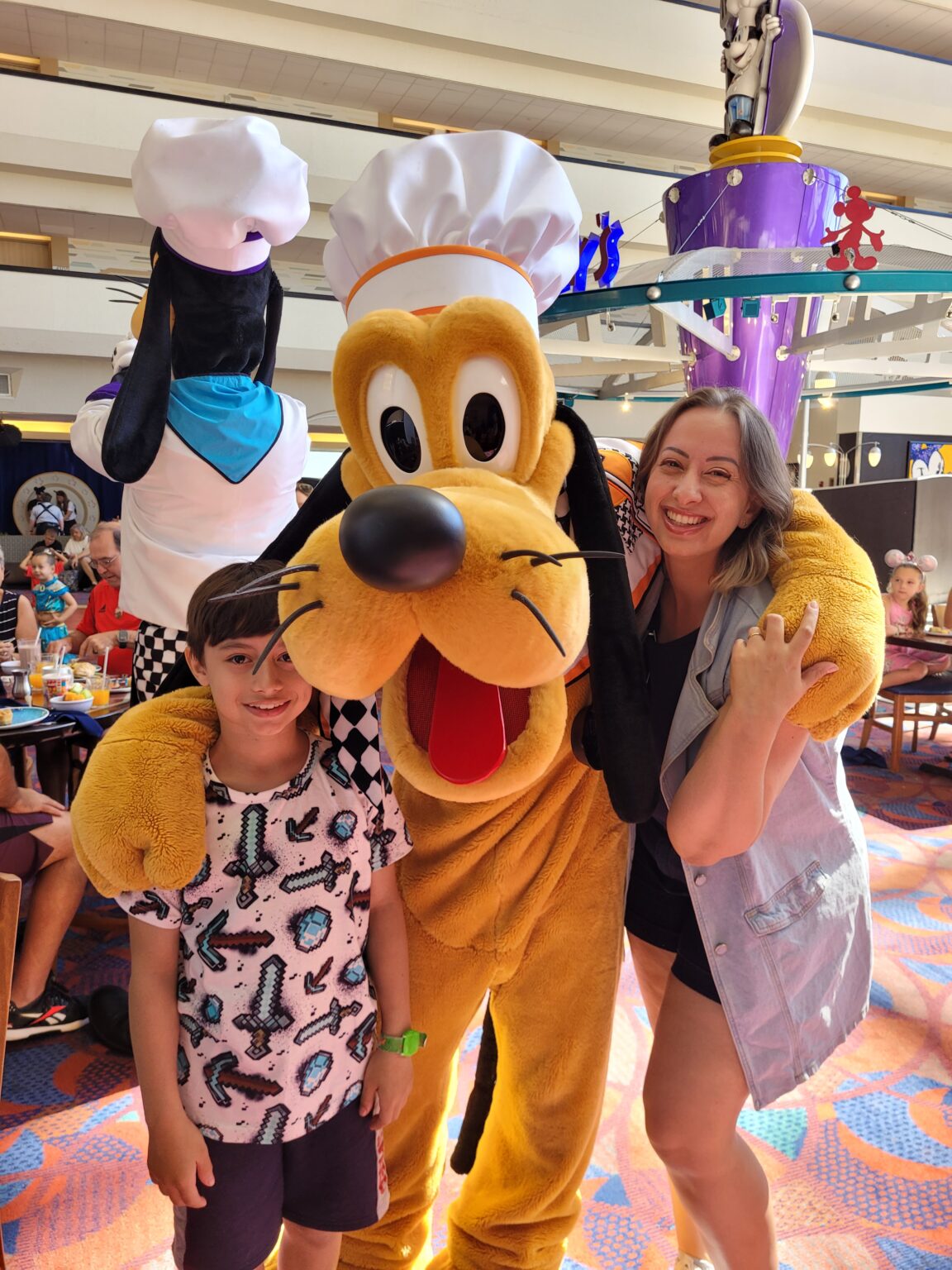 Mãe e filho com o Pluto no Restaurante Chef Mickey's