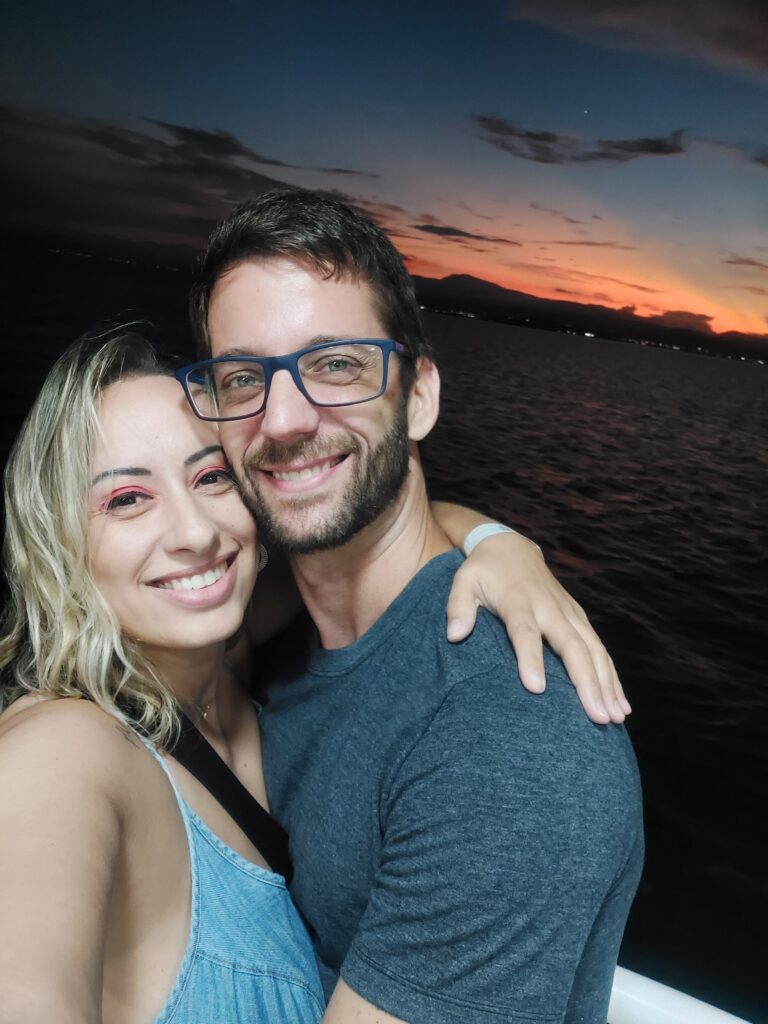 Casal no catamarã de Florianópolis ao pôr-do-sol